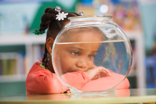 Schoolgirl (4-5) looking at goldfish, close-up